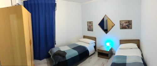 马尔扎梅米La Casa di Angelica Marzamemi的一间设有两张床和蓝色窗帘的房间
