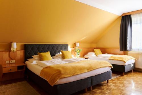 巴特布卢毛温泉绿洲加尼酒店的黄色墙壁客房的两张床
