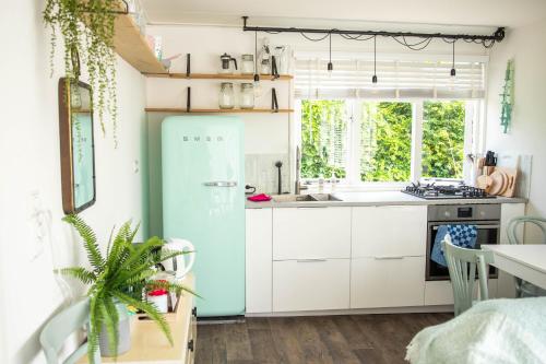 奥德多普Strand-chalet Luna - 700 mtr van het strand van Ouddorp的厨房配有白色橱柜和蓝色冰箱。