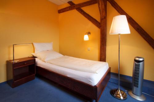 Kalbe“祖姆普特库臣”兰德酒店的一间小卧室,配有床和灯