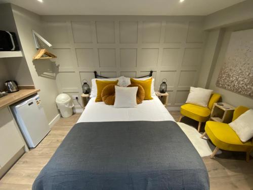 奥本Greenbank, Lower Greenbank Guest Suite的一间卧室配有一张大床和两张黄色椅子