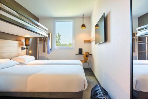 巴黎Ibis Budget Paris porte de la Chapelle - Aréna的酒店客房设有三张床和窗户。