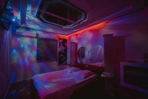 梅阿利亚达Motel Príncipe Encantado的卧室配有粉红蓝色的灯光和一张床