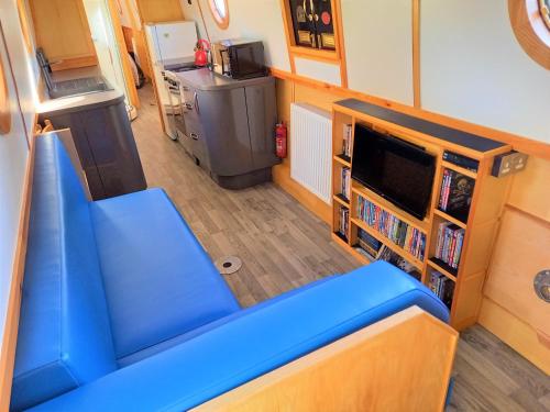 沃里克Smoke (Rowington Narrowboats)的客厅配有蓝色的沙发和电视