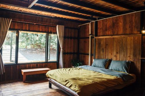 金兰Villa Đảo Hoa Vàng Cam Ranh - Venuestay的卧室配有一张床铺,位于带木墙的房间内
