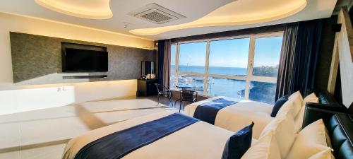 西归浦市Elren Hotel Jeju的酒店客房设有两张床和大窗户。