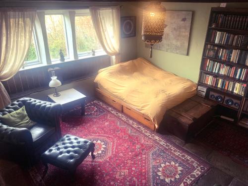 海伯敦桥Nutclough Cottage - Log Fire and Valley View - Sleeps 2的一间卧室配有一张床、一把椅子和一个书架