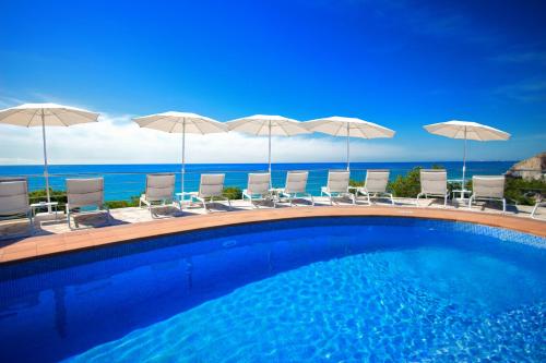 比利亚霍约萨赛维格里普蒙蒂博里酒店的一个带椅子和遮阳伞的游泳池以及大海