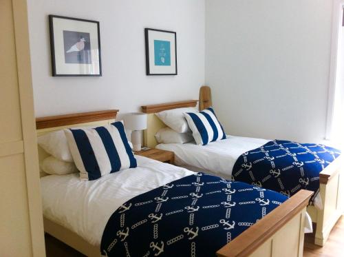帕兹托Harbour Retreat Padstow - Entire Apartment in the beautiful old town of Padstow Harbour的一间卧室配有两张带蓝白色枕头的床