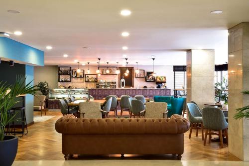科英布拉Tivoli Coimbra Hotel的一个带沙发和椅子的大堂以及一间餐厅