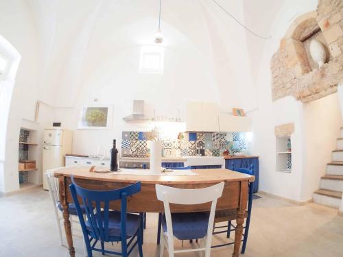 莱韦拉诺Antica Dimora Salentina的厨房配有木桌和蓝色椅子
