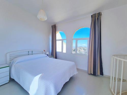 阿桂拉斯Catalejo chalet casa rural 18 plazas的一间白色卧室,配有床和2个窗户