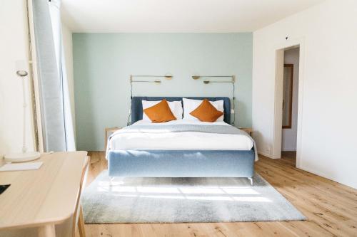 AubonneHemma的一间卧室配有蓝色的床和橙色枕头