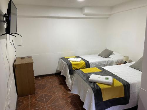 巴耶纳尔Hostal CECIL +的一间设有两张床和电视的房间