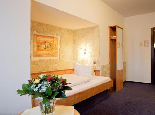 布伦瑞克德意志豪斯酒店的配有一张床和花瓶的酒店客房