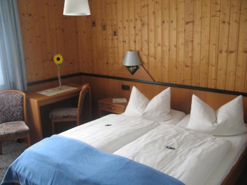 塞尔比茨Gasthof-Pension Leupold的卧室配有白色的床和带台灯的书桌
