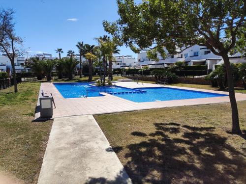 阿尔阿马德穆尔西亚Lovely 3 Bedroom Apartment on Golf Resort的一座游泳池,位于一个种有树木和房屋的庭院内
