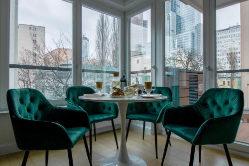 华沙Warsaw Seasons by Alluxe Boutique Apartments的带窗户的客房内的一张桌子和绿色椅子