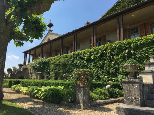 CeyzériatClos de Mont July, chambres avec vue et terrasse dans demeure historique的前面有树 ⁇ 和花的建筑