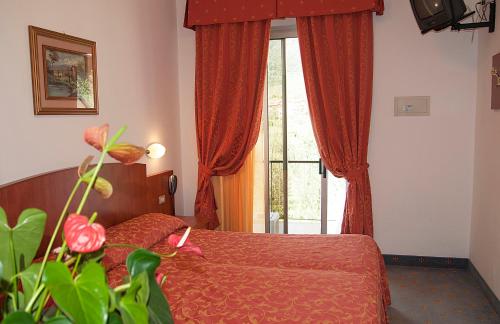 利莫内-苏尔加达花园酒店的一间卧室配有床和红色窗帘的窗户