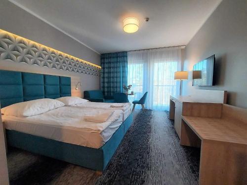 斯维诺乌伊希切Modern studio in the Caesers Garden resort, Swinoujscie的酒店客房设有一张大床和一张书桌。