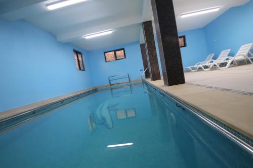 布什泰尼Complex Cochet的室内游泳池拥有蓝色的墙壁和白色的椅子