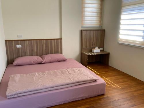 马公欣雅民宿的卧室内的一张带粉色床单和木制床头板的床