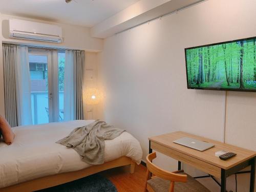 东京Dash Living Shinjuku的一间卧室配有一张床、一张桌子和一台电视