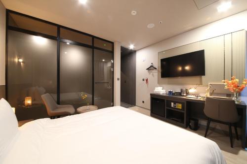 釜山City Hotel the Busan Metro的一间卧室配有一张床、一张书桌和一台电视