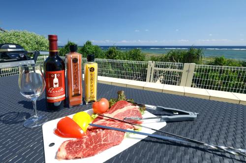 德之岛オーシャンヴィラ徳之島-Ocean Villa Tokunoshima-的桌子上放着一盘肉和蔬菜,放着酒瓶