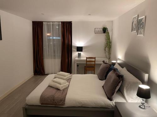 伦敦City airport serviced apartment London的一间卧室配有一张大床、一张桌子和一个窗户。
