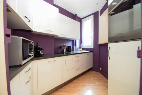 万塞讷Top location near ParisSuperb cosy 2p apartment的厨房配有白色橱柜和紫色墙壁
