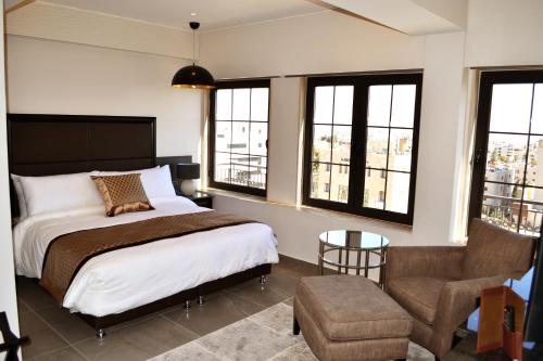 安曼Ambassador, a Boutique Hotel的一间卧室配有一张床、一把椅子和窗户。
