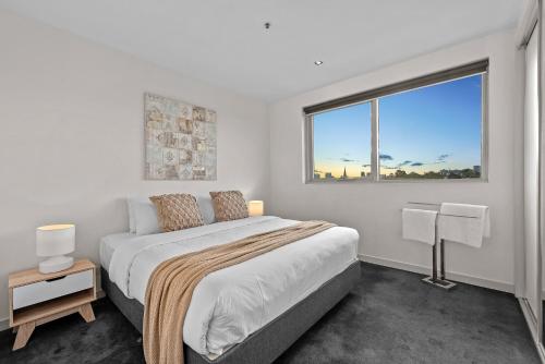墨尔本SXY独家住宿公寓的白色的卧室设有一张大床和一个窗户