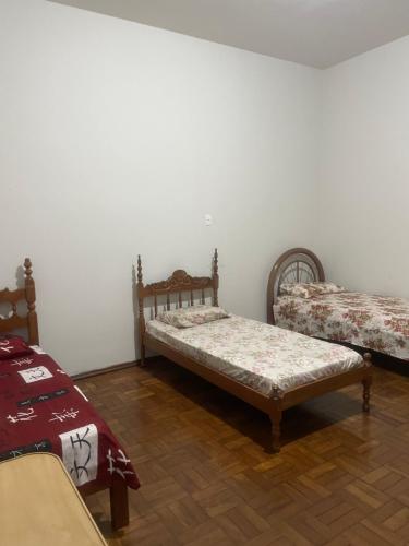 帕苏斯Apartamento Temporada的配有白色墙壁和木地板的客房内的两张床