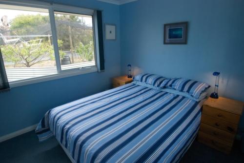 Sandford班布拉礁度假屋的蓝色的卧室设有床和窗户