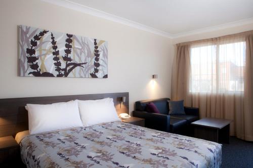Narellan纳雷兰汽车旅馆的配有一张床和一把椅子的酒店客房