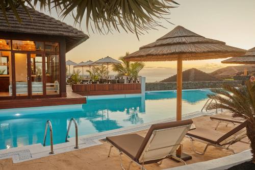 卡列罗港Secrets Lanzarote Resort & Spa - Adults Only (+18)的一个带两把椅子和遮阳伞的游泳池