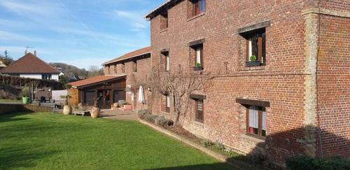 Rouxmesnil-BouteillesHôtel Restaurant l’Éolienne的前面有绿色草坪的砖砌建筑