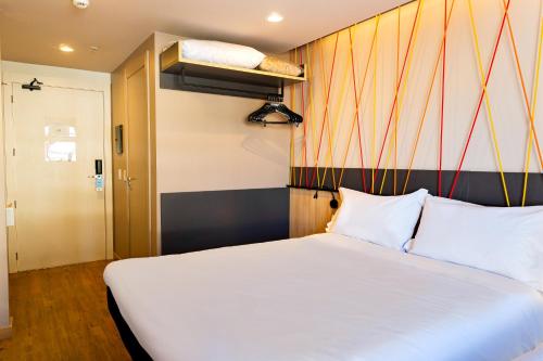 阿雷格里港ibis Styles Porto Alegre Moinhos de Vento的卧室配有白色的床和条纹墙