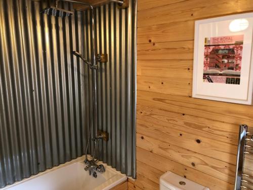 滕比The Chalet @ Giltar Grove Country House的一间带木墙、浴缸和卫生间的浴室