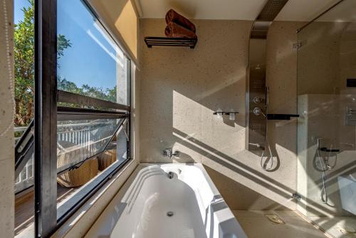 罗纳瓦拉SaffronStays Hillside Harriers, Lonavala - A Frame chalets with bathtub for couples的带浴缸的浴室和窗户。