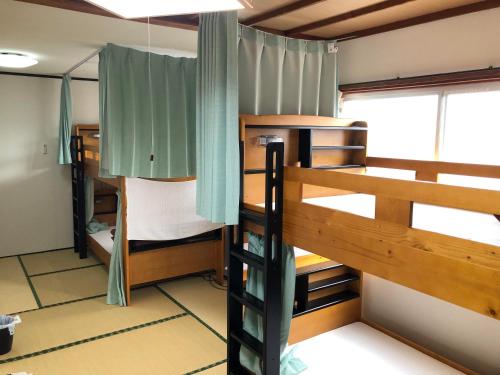 指宿市ゲストハウスまちかど Guest House MACHIKADO的客房设有两张双层床和一扇窗户。