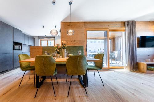 布鲁尼科Rienz Alpine City Lofts的一间带木桌和绿色椅子的用餐室