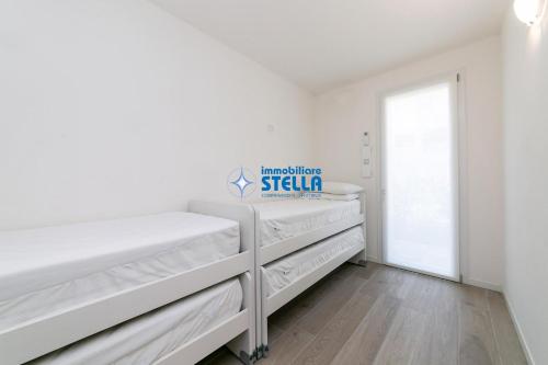利多迪耶索罗Villaggio Le Tropezien的白色的卧室设有白色的床和窗户。