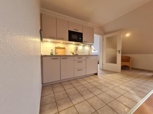 格洛米茨"Pappelhof - Whg 8"的厨房配有白色橱柜和瓷砖地板。
