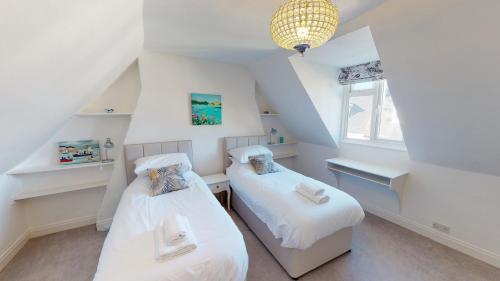 锡德茅斯Bethany Cottage的阁楼间设有2张床和白色墙壁