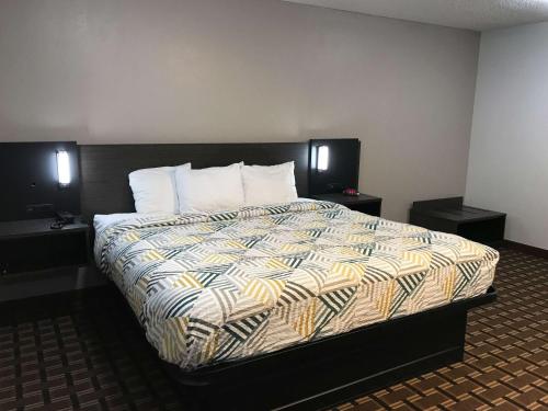 图珀洛Studio 6 Suites Tupelo, MS的一间卧室配有一张大床、两个床头柜和两张桌子