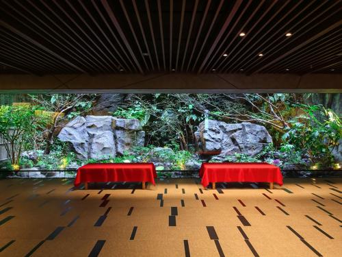 京都京都索拉利亚西铁尊贵酒店的两张红色桌子,在一堵植物墙前