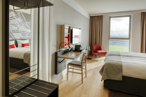 霍夫多普IntercityHotel Amsterdam Airport的酒店客房带一张床铺、一张书桌和一间卧室